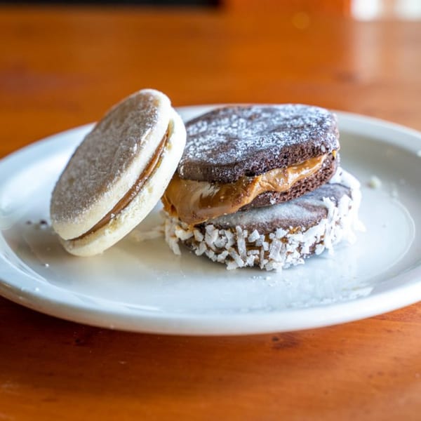 Three Peruvian alfajores on a white plate, one light-colored and two dark chocolate with dulce de leche.